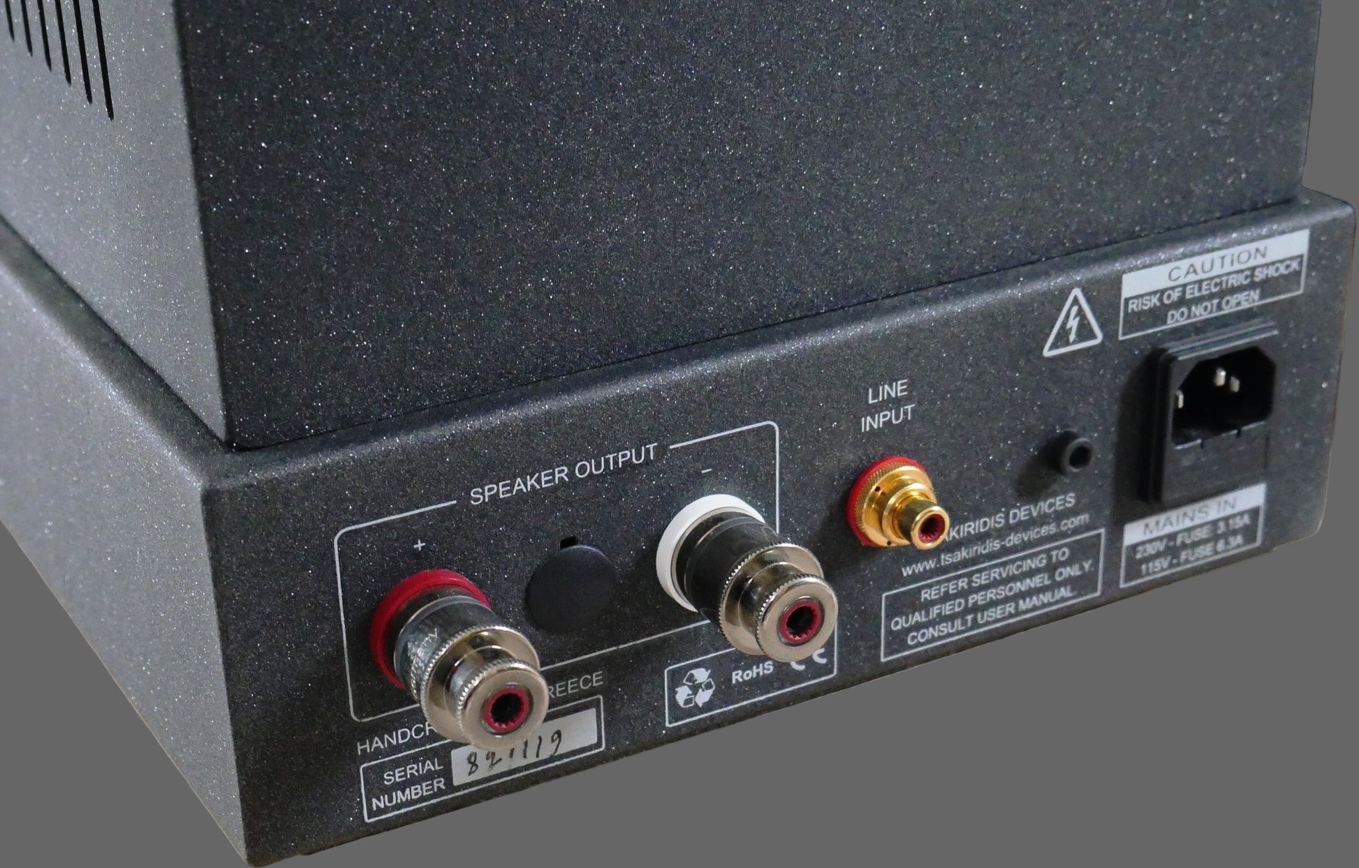 Back panel of a power amplifier with various connectors on a wooden stand.